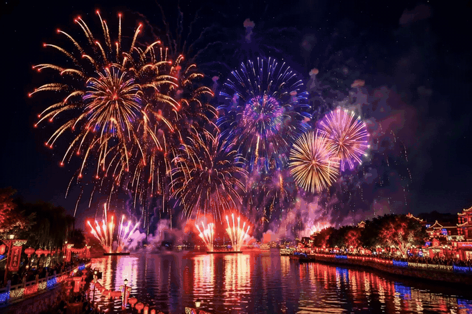 Happy New Year 2027 fireworks GIF — colourful fireworks over a river with sparkling reflections, golden Happy New Year 2027 text